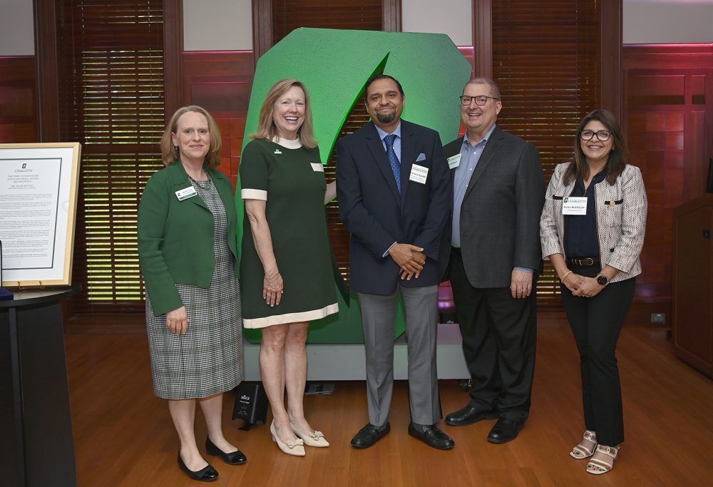 Juan Vivero-Escoto stands smiling with University leadership.