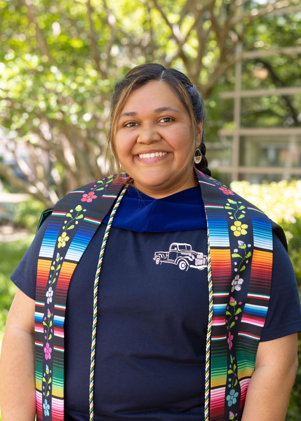 Yelixza Avila wears a shirt with an image of a 1941 pickup truck, under her graduation stole, hood and cord.