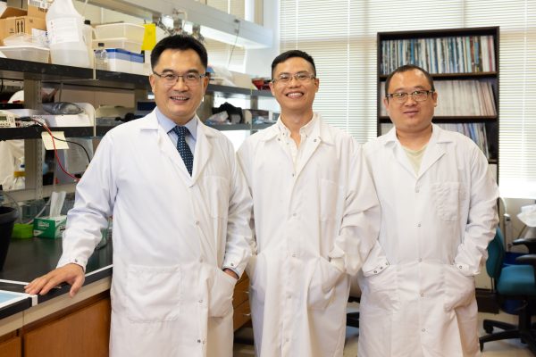 3 scientists wear lab coats in the Yan lab.