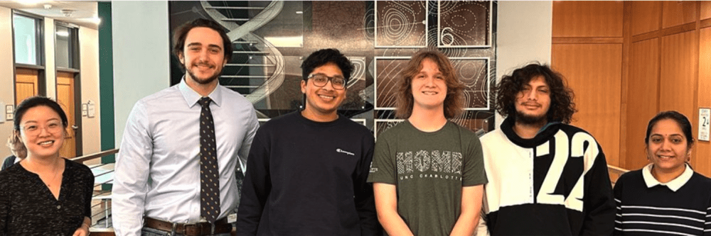 A smiling group of students in front of the Science Wall