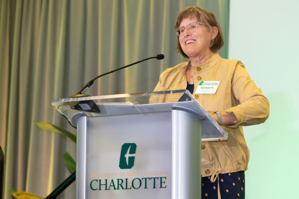 Susan Michael smiles giving her speech at the podium with the Charlotte logo