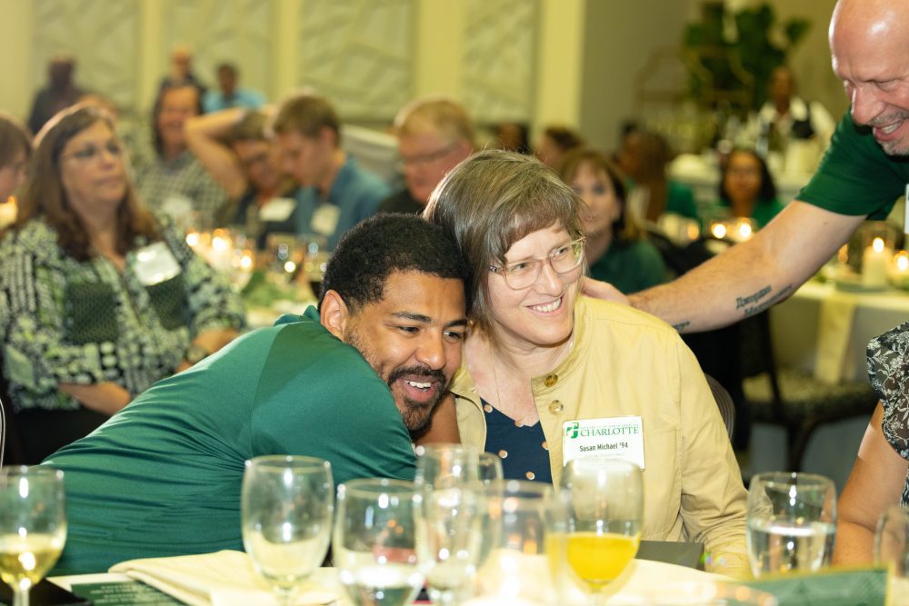 Susan gets a hug at her table from two other faculty after the win.