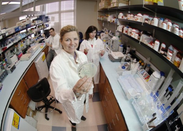 Christine Richard stands in her lab holding a petri dish.