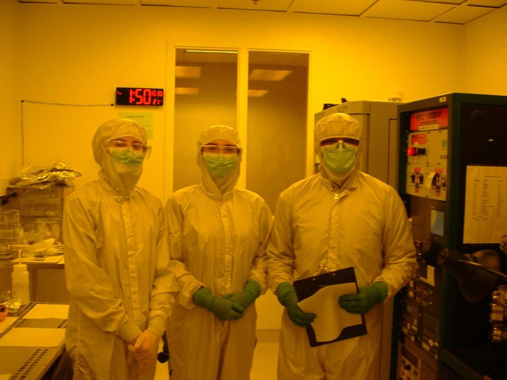 3 physics students in full tyvek suits in the physics lab clean room.