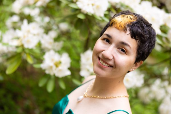 Taylor Yonemura smiles while wearing a green dress in the UNC Charlotte Botanical Gardens.