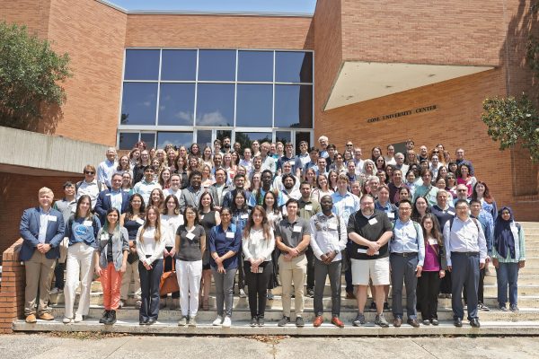 Group photo of the 130 attendees of the Symposium lined up on the Cone University Center steps.