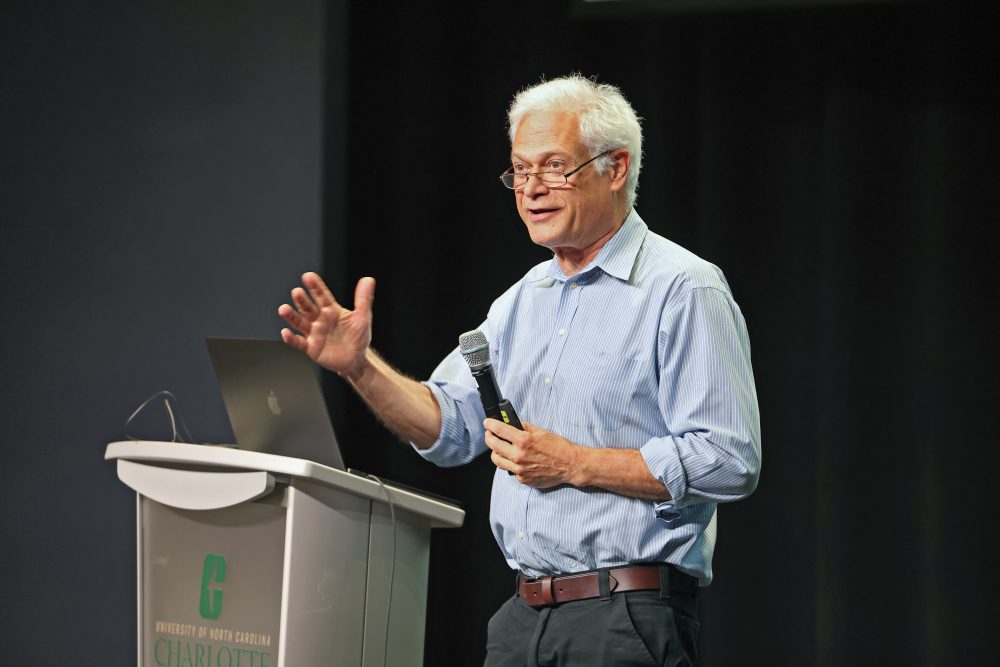 Alan D. D'Andrea holding a microphone and speaking on stage.