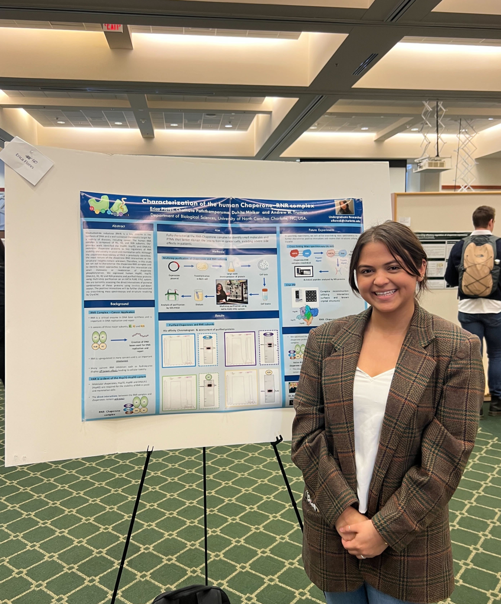 Flores posing with her poster at the 2023 ABSGS Annual Biological Sciences Research Symposium