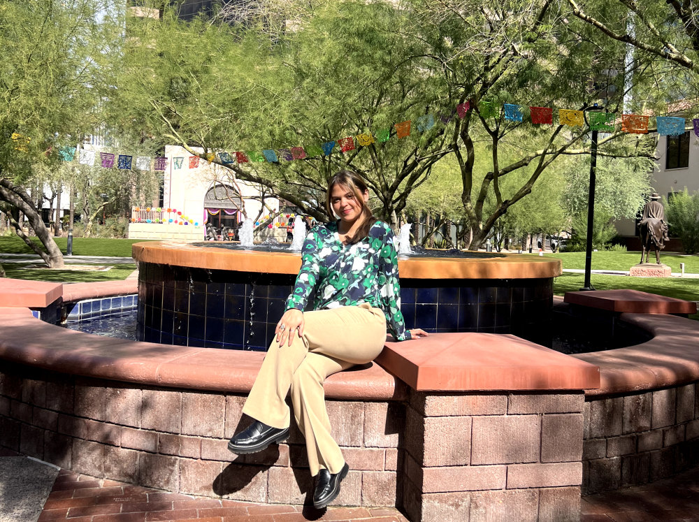 Erica Flores sitting on the side of a fountain outside at the SACNAS conference in Phoenix, Arizona.