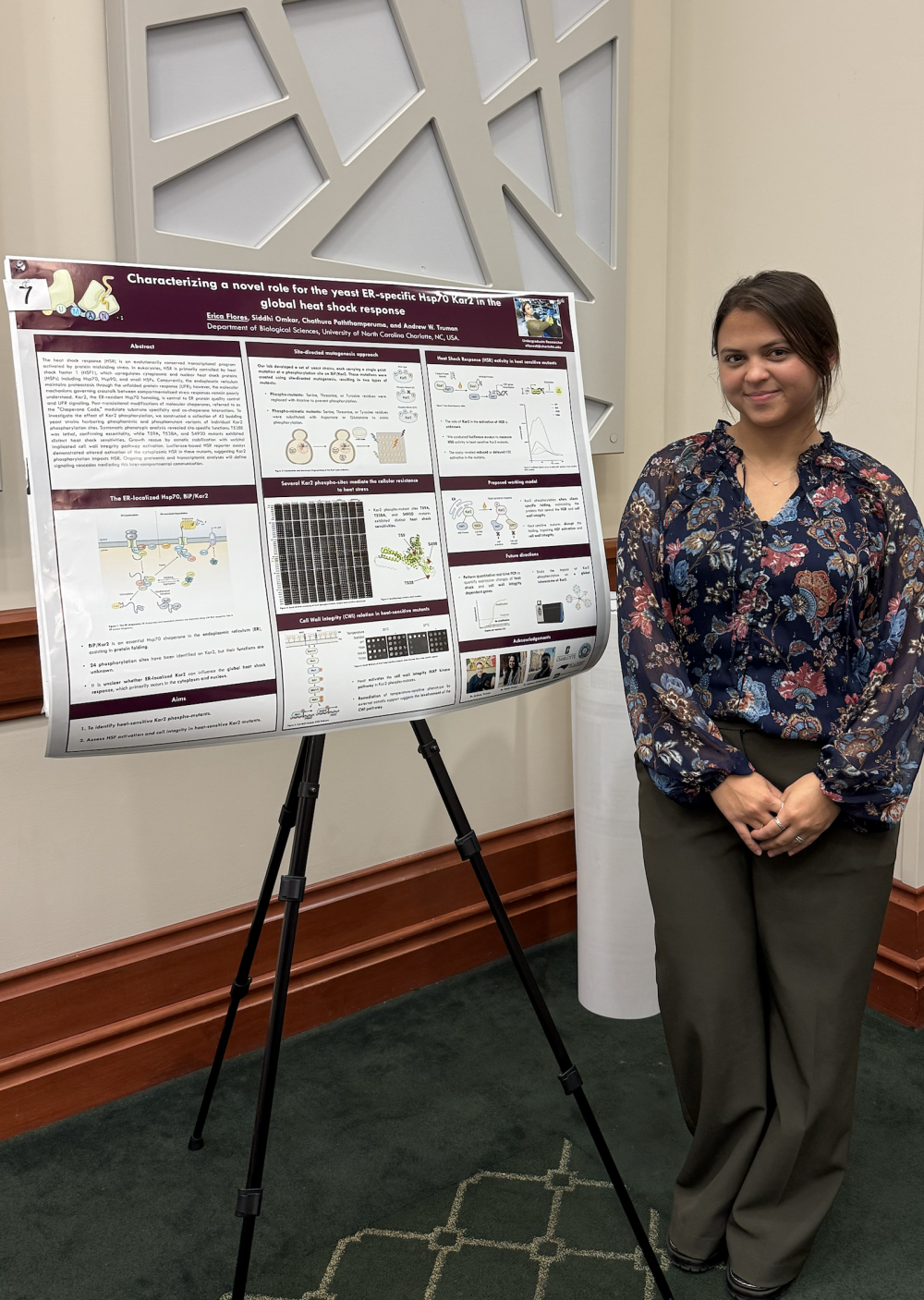 Flores posing with her poster at the 2025 ABSGS Annual Biological Sciences Research Symposium