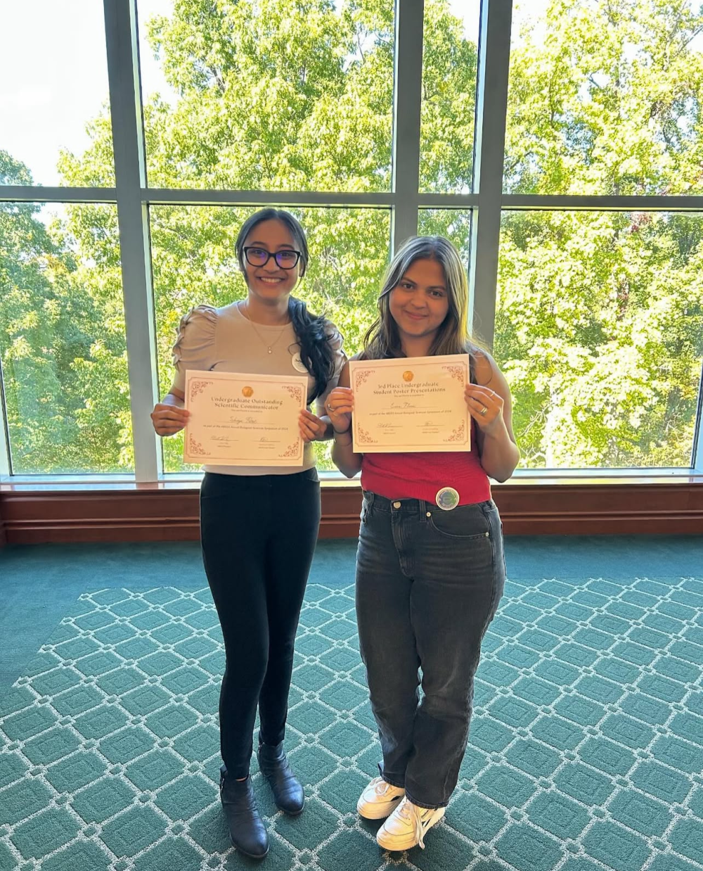 Erica Flores and Shreya Patel posing with their awards from the 2024 ABSGS Annual Biological Sciences Symposium