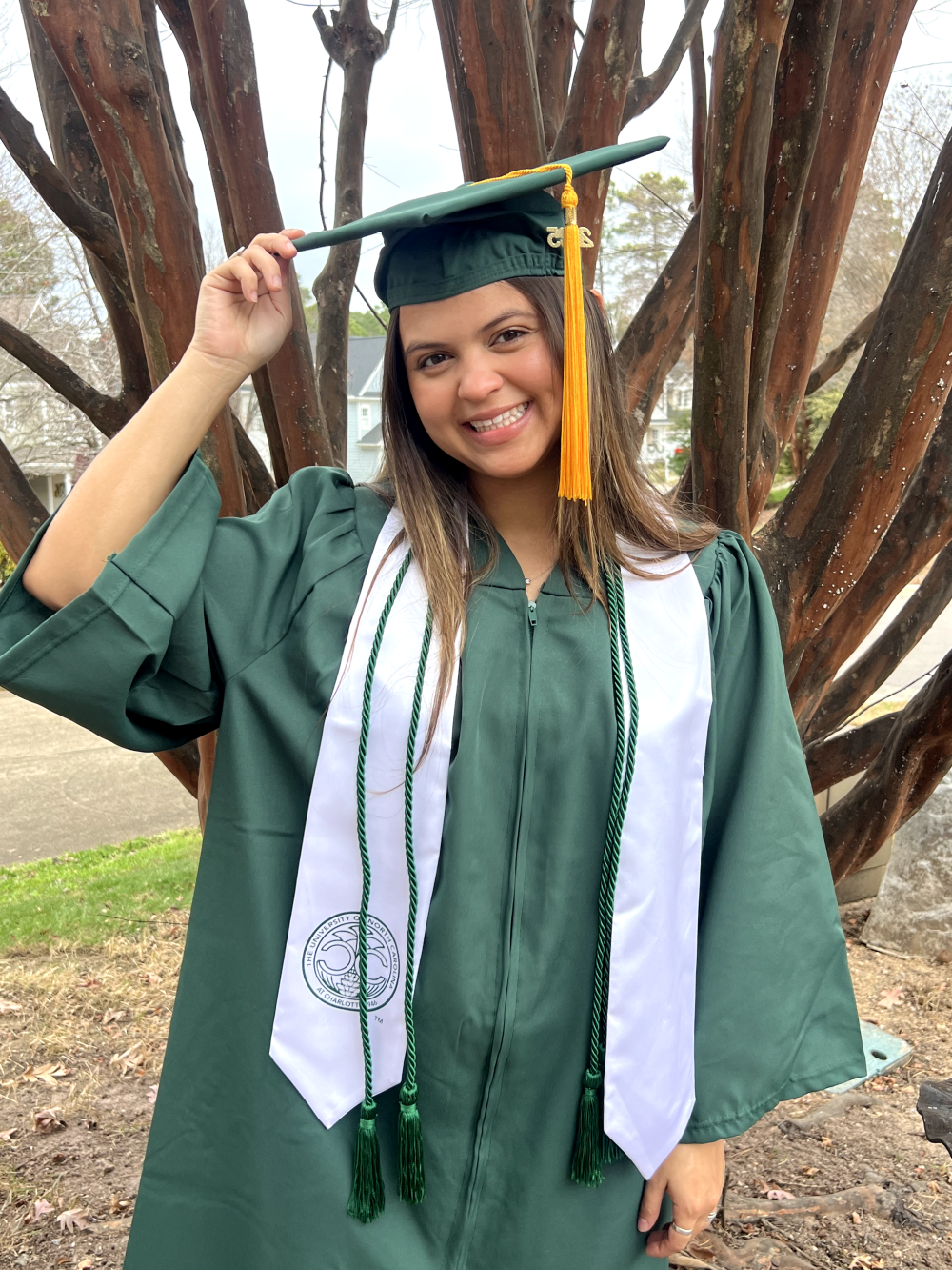 Erica Flores posing with her green graduation cap and gown