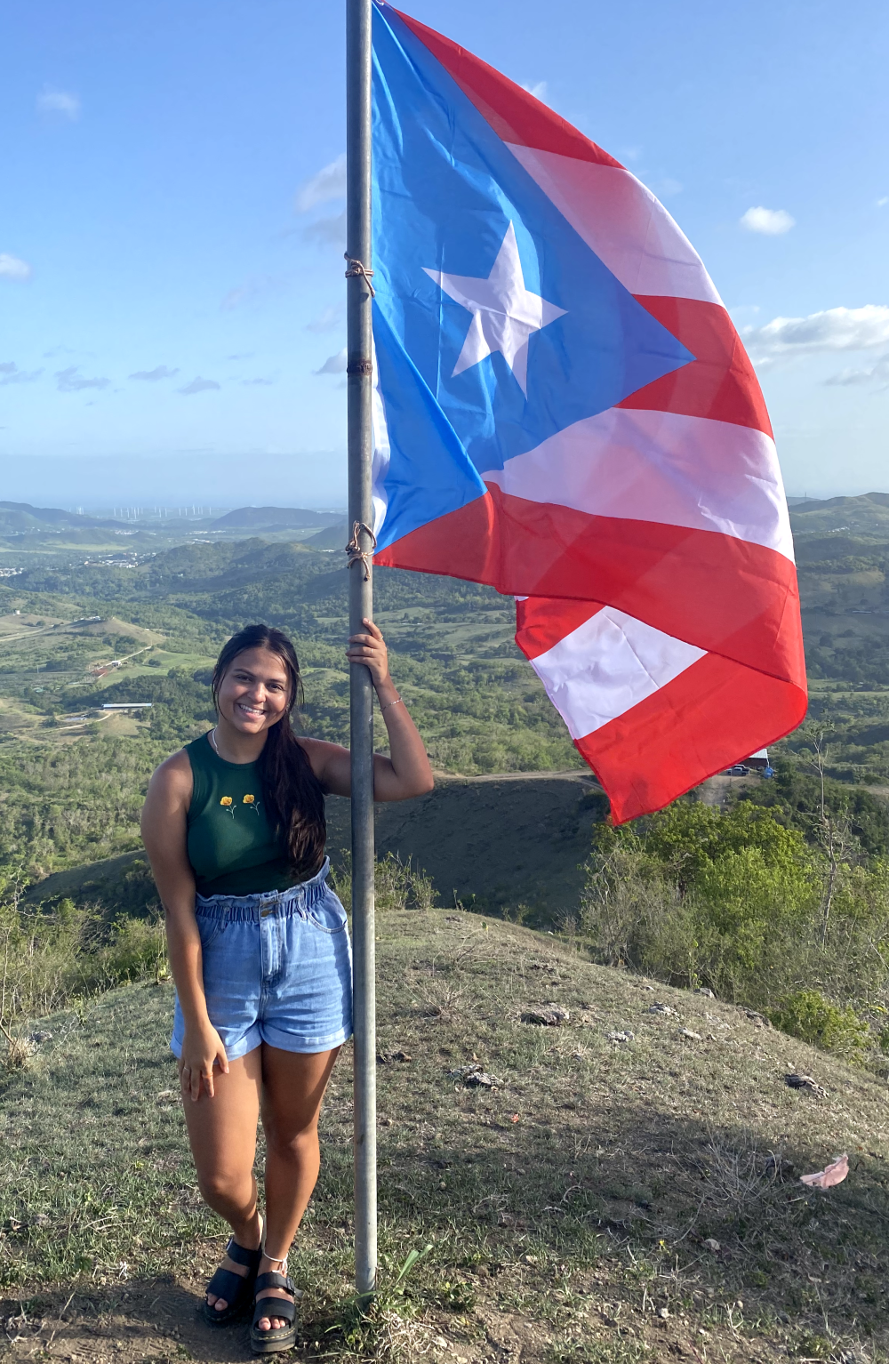 Erica Flores standing on a mountain with a Puerto Rican flag