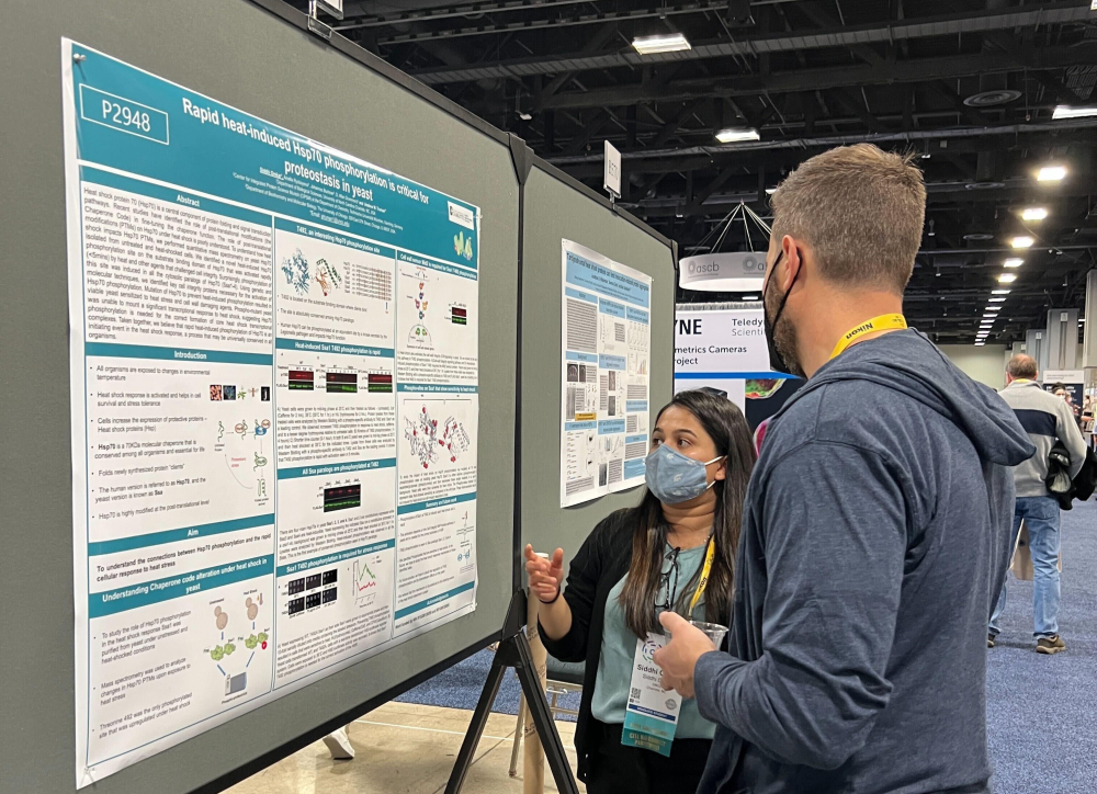 Omkar presents her research poster to a conference attendee.