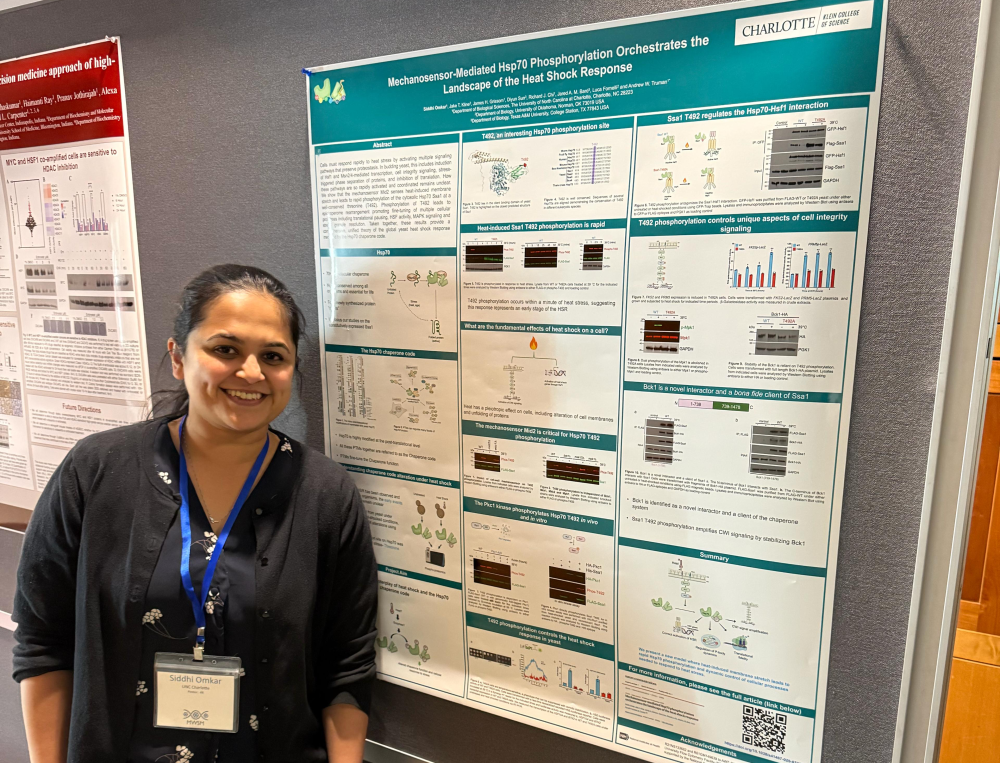 Omkar smiling next to her research poster at a conference.