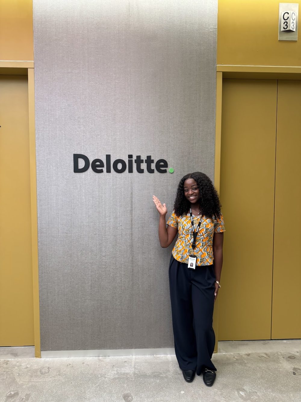 Ntasin gesturing at a Deloitte sign.