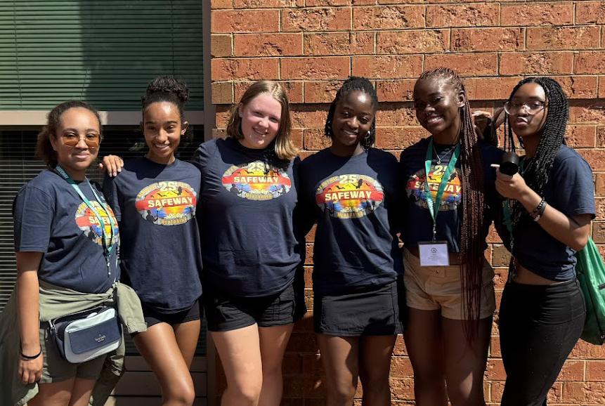 Ntasin poses with five SAFE mentees outside in front of a brick wall.