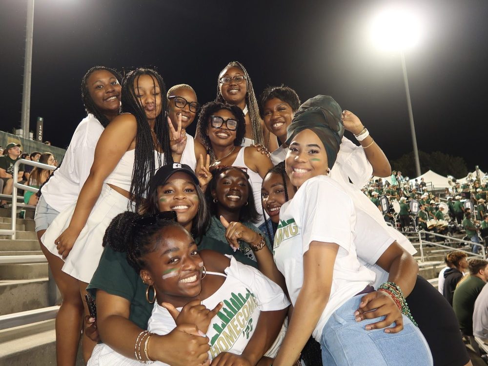 Ntasin and a group of friends posing in the stands of a football game.