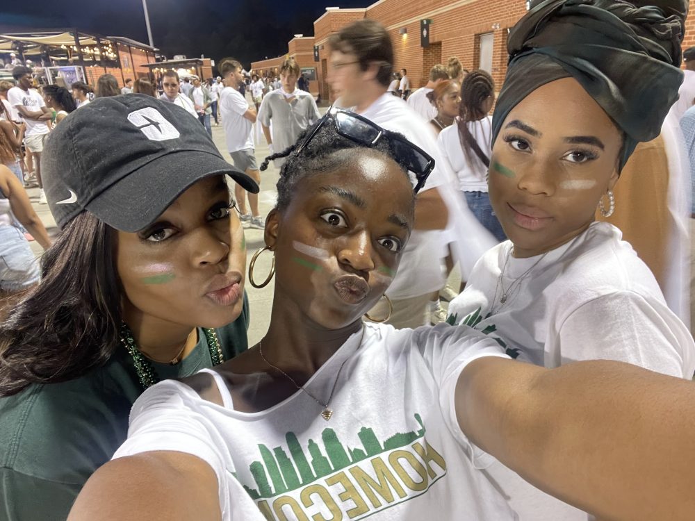 Ntasin and two friends take a selfie at a football game.