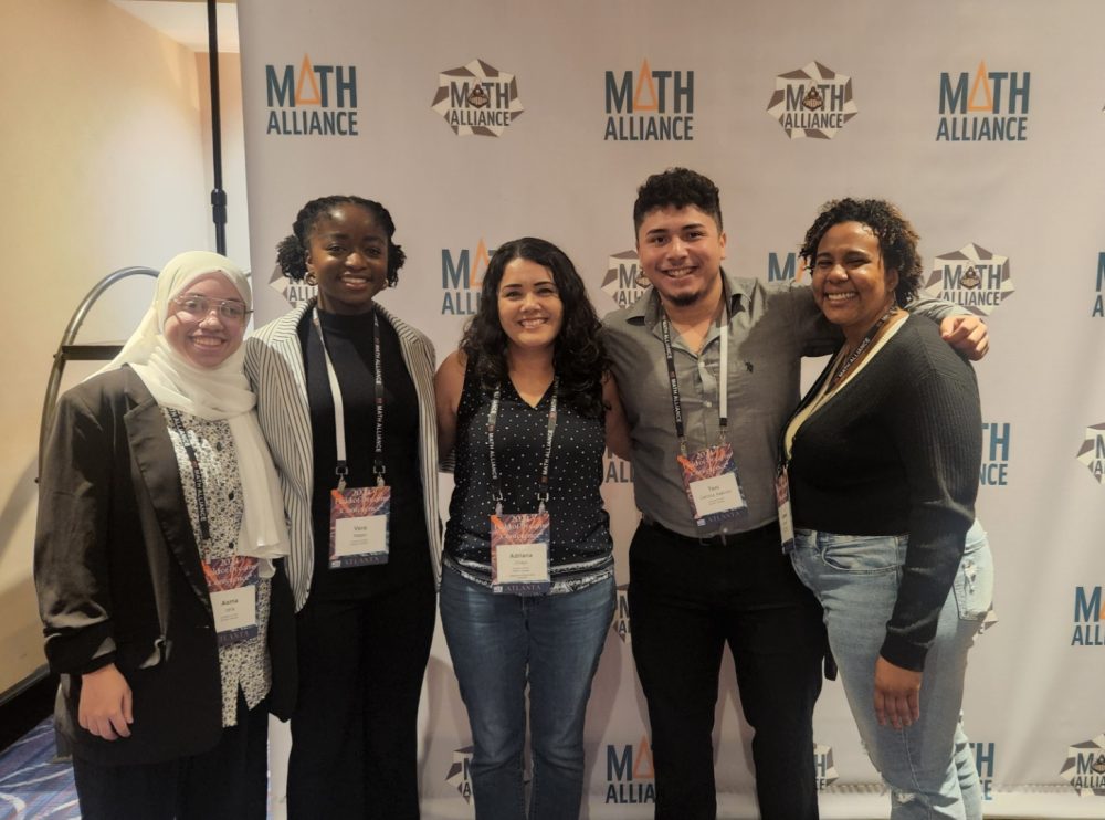 Ntasin and four others stand in from of a backdrop that says "Math Alliance."