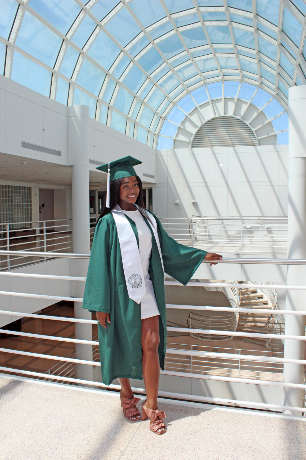 Ntasin poses in cap and gown on the top floor of the Fretwell building. 