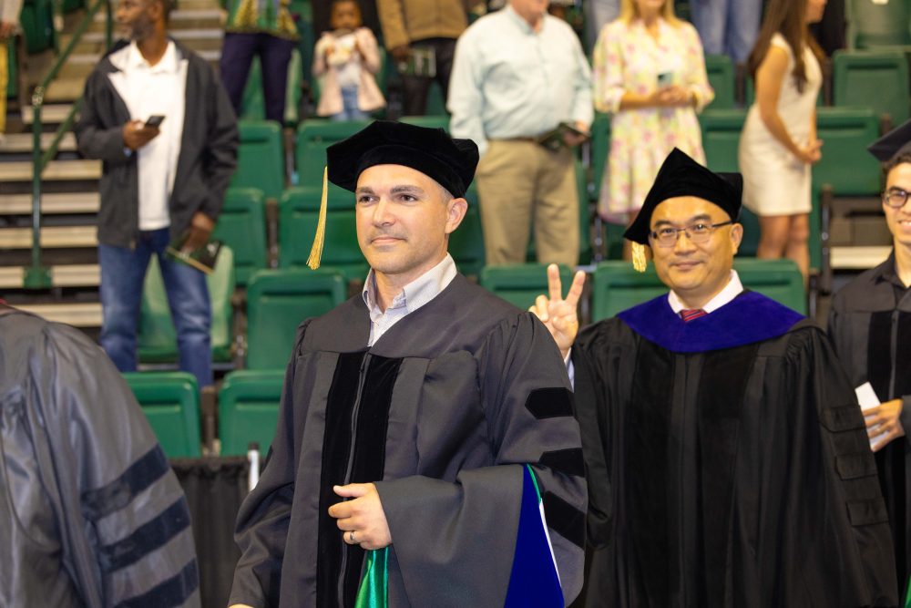 A Ph.D. candidate and their advisor, Shan Yan, who flashes a peace sign.