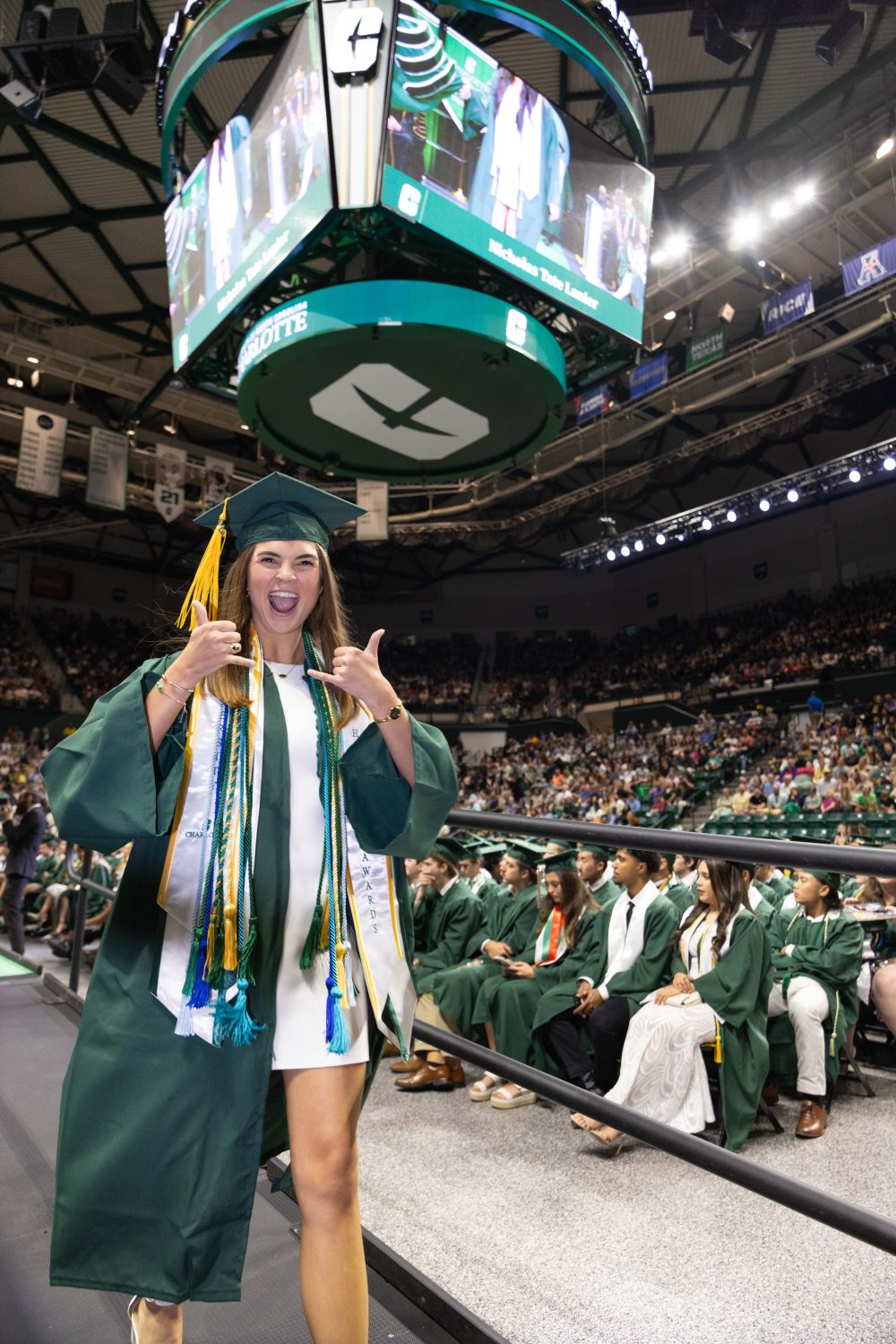 A smiling UNC Charlotte graduate from the Klein College of Science crosses the stage. 