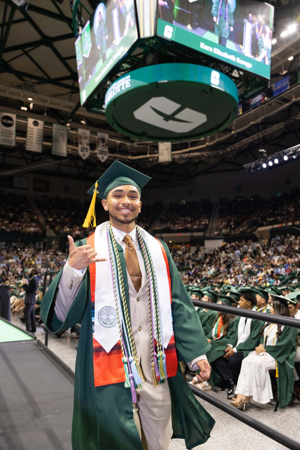 A smiling UNC Charlotte graduate from the Klein College of Science crosses the stage. 