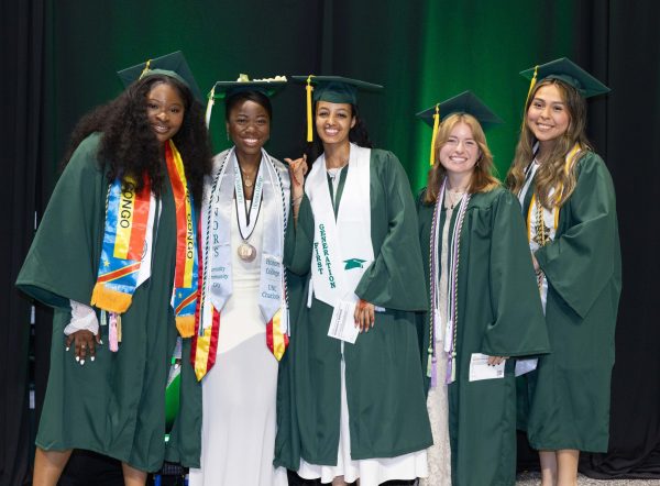 A group of five Klein College graduates wearing regalia at UNC Charlotte's graduation.