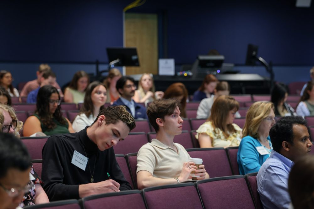 Photo of the crowd writing notes and listening to the speakers.