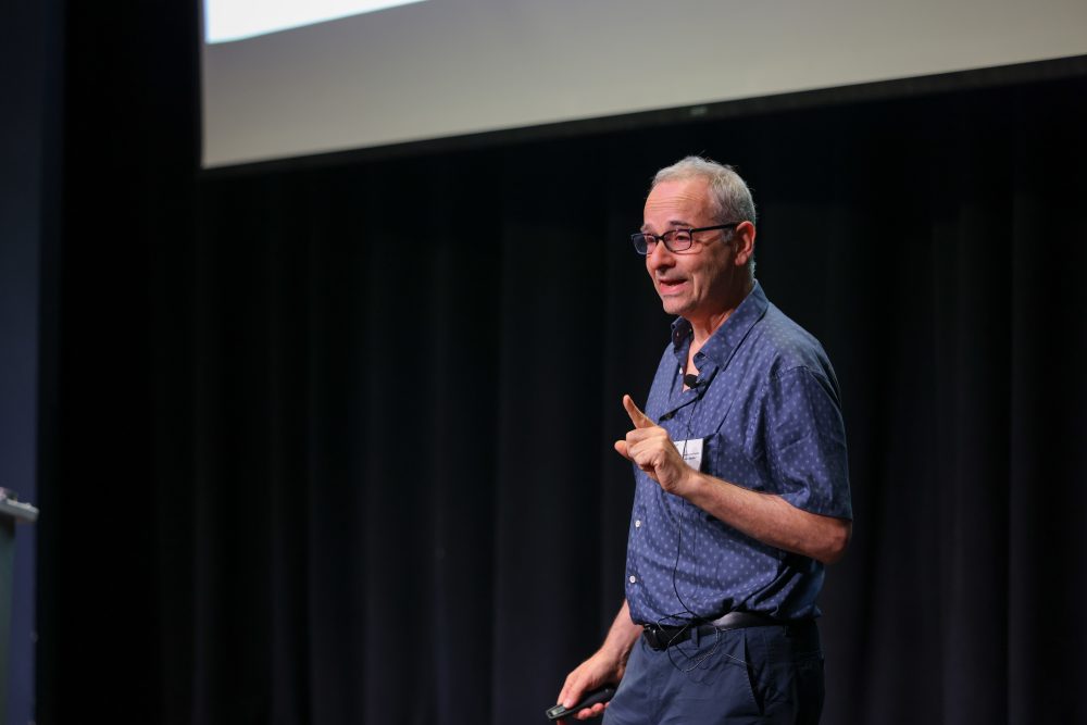 A close up of Nussenzweig on stage and speaking to the crowd.