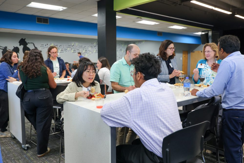 Attendees eating and talking at a table during the networking event.