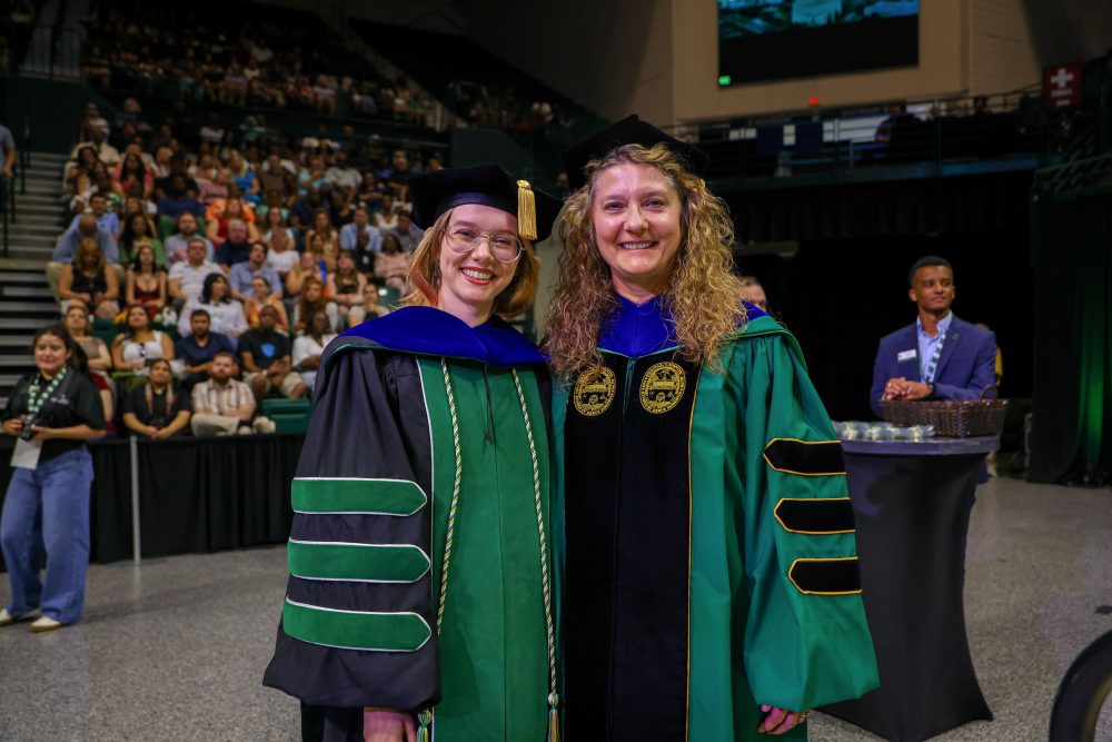 Hal West-Page, three time UNC Charlotte graduate, poses with Klein College of Science Dean Bernadette Donovan-Merkert after crossing the stage during the August 2026 commencement ceremony.