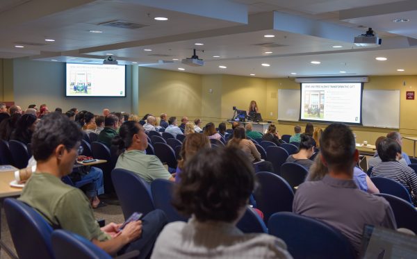 UNC Charlotte Klein College of Science Dean Bernadette Donovan-Merkert kicks off the 2026-27 academic year with KCOS faculty and staff, addressing the room of employees seated in a lecture hall while she speaks from a podium.