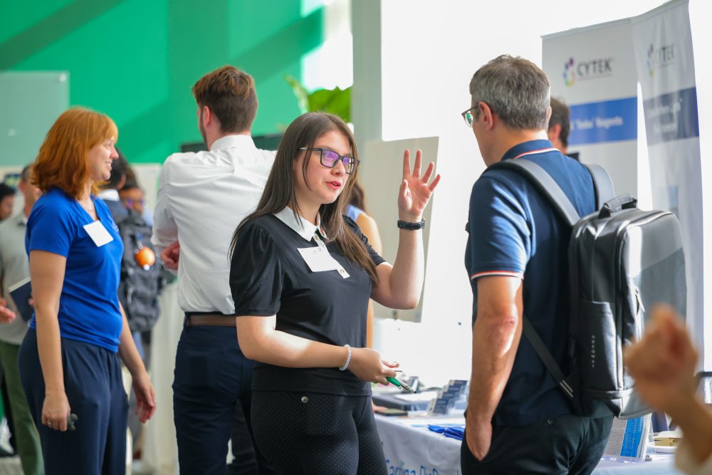 Sofia Jimenez-Murillo wears a black shirt and glasses and gestures while speaking to another individual at the 2026 Biomedical Sciences Symposium.