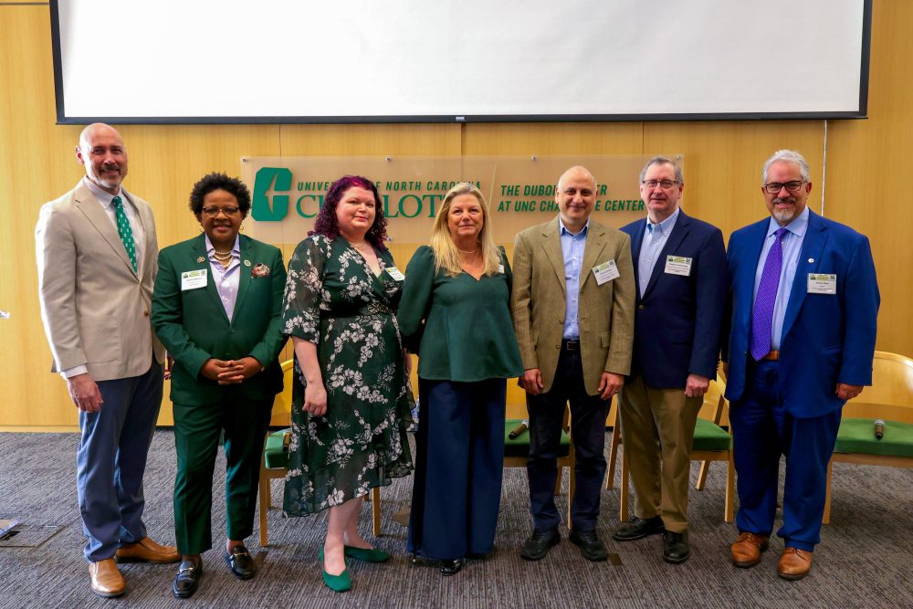 The organizers and plenary speakers for the 2026 Biomedical Sciences Symposium stand in front of the UNC Charlotte logo at the Dubois Center on Sept. 14.